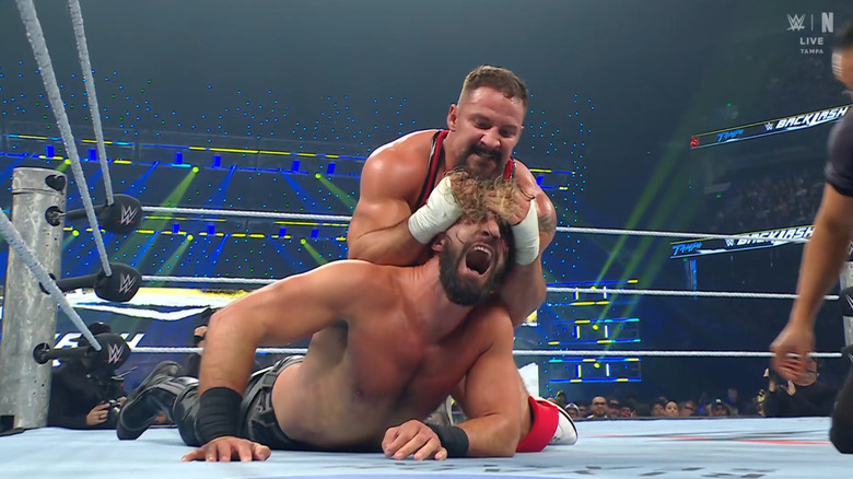 Breakker wearing down Rollins with a submission hold in the ring
