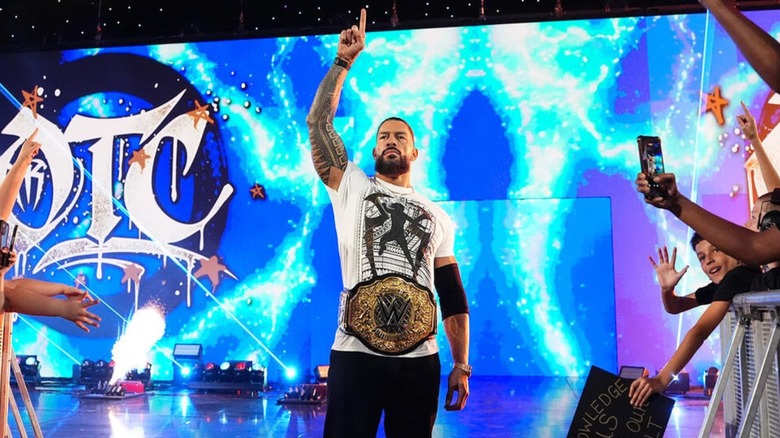Roman Reigns poses on the stage, World Heavyweight Championship around his waist, before a contract signing segment on "WWE Raw."