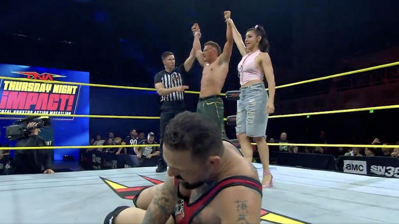 Stacks and Grace with their hands raised standing behind Marella