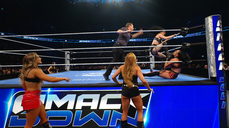 Paige firing off stomps on Jayne in the corner as Henley and Reid watch from the outside.