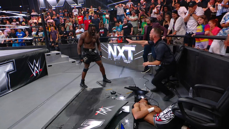 Carver standing over Prosper after powerbombing him through the announce desk