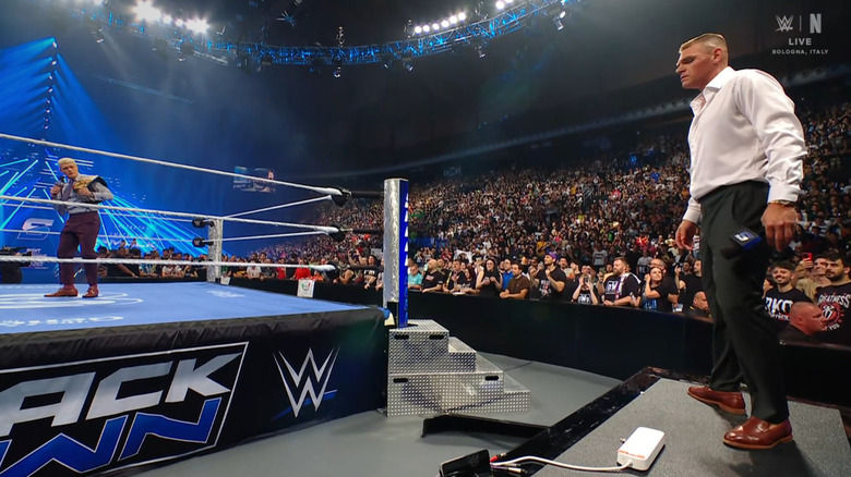 GUNTHER standing on teh announce desk and staring down Rhodes in the ring