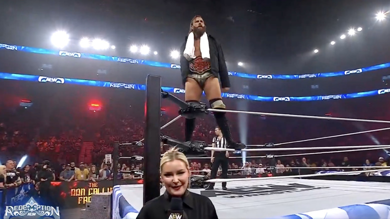 Davis posing on the ropes as Renee Paquette stands in front of him outside the ring