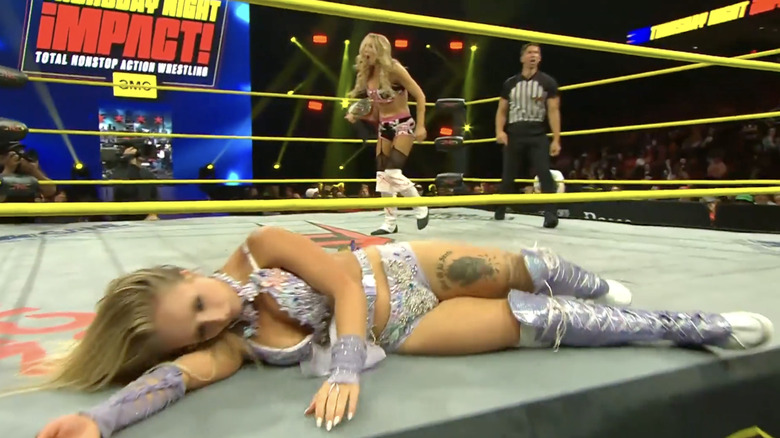 Allie standing over Heather in the ring