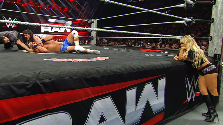 Dominik wearing down Hendry with a submission hold as Morgan watches from the outside