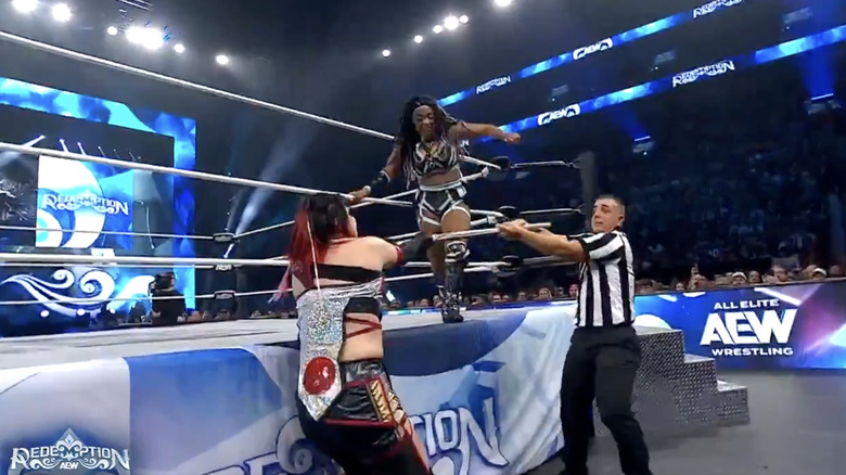 Shida and the referee playing tug of war over Shida's kendo stick as World stands on the ring apron
