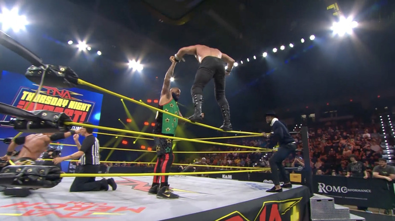 Kazarian distracting the referee as Elijah walks the ropes with Francis in tow