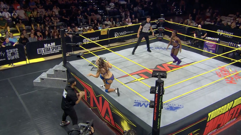 Alisha on the ring apron as Stone is in the ring and Eddie is on the outside