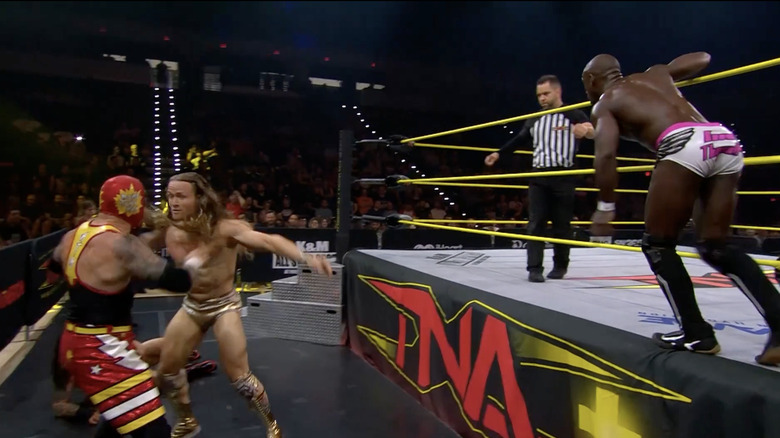Mr. Elegance and Hometown Man as Swann is on the ring apron